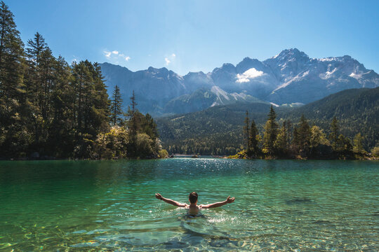 Man swimming in a beautiful mountain lake in the middle of the nature in the Bavarian Alps, Germany. Famous destination in Europe