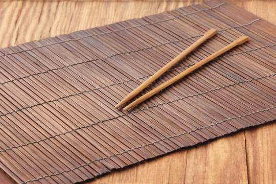 Sushi Sticks On Brown Bamboo Food Placemat On Wooden Table.