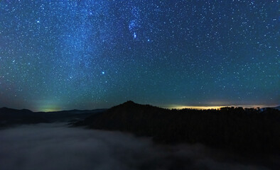 A beautiful starry night in the mountains on top with beautiful scenery and fog.