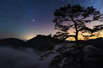 Fototapeta na wymiar A beautiful starry night in the mountains on top with beautiful scenery and fog.