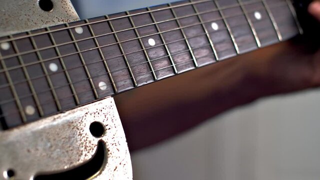 Man Playing Old Metallic Resonator Guitar with Slide Close Up