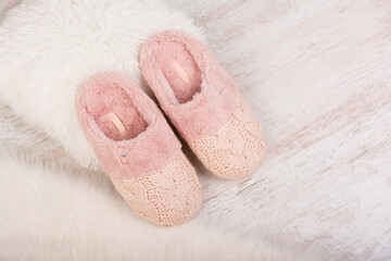 Pair of warm female slippers on white furry carpet