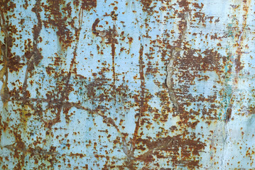 Old iron sheet with peeling brown paint and rusty spots.
