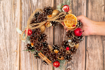 Interior New Year or Christmas wreath. Elements from natural materials. Pine and spruce cones, cinnamon, orange peel. Photo for postcards.