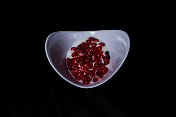 Pomegranate seeds in white bowl with yogurt