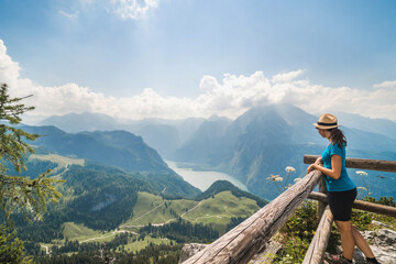 Girl standing on the top of a cliff watching a beautiful mountain scenery in the bavarian Alps