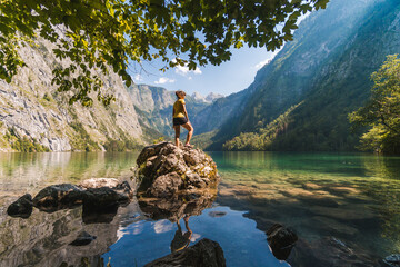 Girl standing on a rock in Obersee lake, watching a beautiful crystal clear water, Bavarian Alps