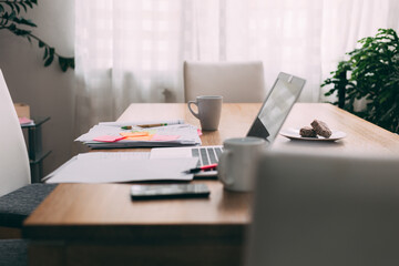 Busy desk in home office space. Laptop and paperwork.
