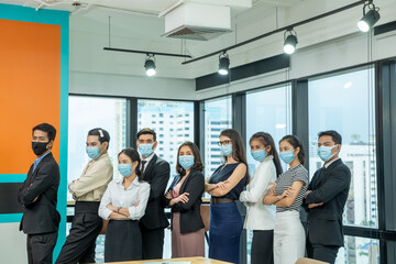 Diverse business people group with face mask protect from Corona virus standing together as team in office,Support and collaboration together to overcome pandemic of Corona virus to reopen business.