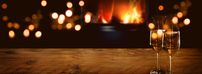 Champagne on rustic wood in front of a log fire with golden bokeh lights. Horizontal background for...