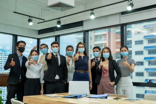 Group of business people standing in the office with face mask protect from Corona virus,Concept of help,Support and collaboration together to overcome pandemic of Coronavirus to reopen business.