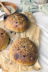 Handmade natural yeast-free sourdough bread made from three types of flour with sunflower seeds. Three loaves of fresh toasted bread on parchment paper. Making bread at home