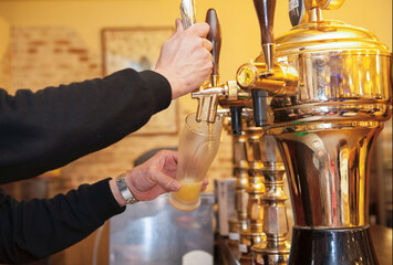 タップ（ビールサーバー）からグラスにビールと泡をなみなみと注ぐシーン　パブ