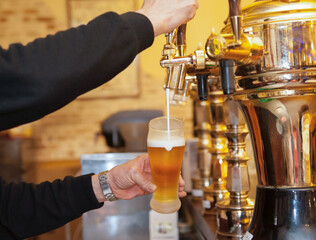 タップ（ビールサーバー）からグラスにビールと泡をなみなみと注ぐシーン　パブ