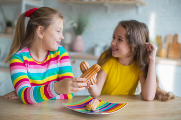 Teen girls together play and eat cakes in the kitchen. Happy kids concept