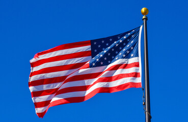 Beautiful large US flag flying in the wind proudly with freedom in red , white blue Stars and Stripes of America land of the free and democracy