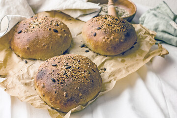 Handmade natural yeast-free sourdough bread made from three types of flour with sunflower seeds. Three loaves of fresh toasted bread on parchment paper. Making bread at home