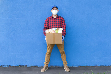 volunteer with a box of food on a blue background, donations