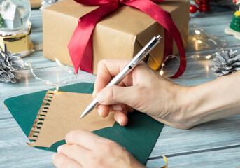 Famale hand writing a Christmas letter on wooden background