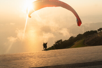 Paraglider take off in the sunset sky against the background of clouds. Paragliding in the sky at...