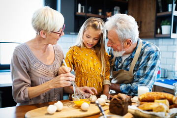 Happy smiling senior randparents playing with their granddaughter