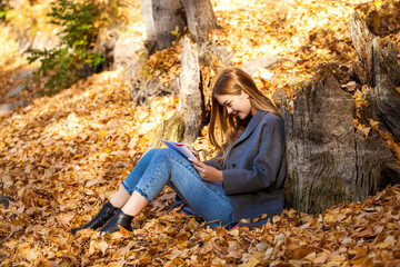 Young girl draws in the album while sitting in the autumn park