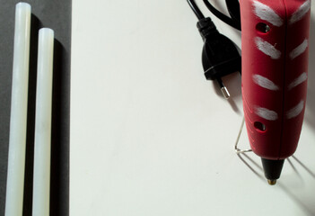 A hot glue gun and some glue sticks on a black and white background
