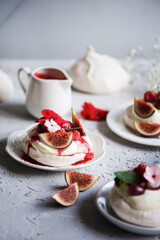 Pavlova cake meringue dessert decorated with edible flowers and fig slices