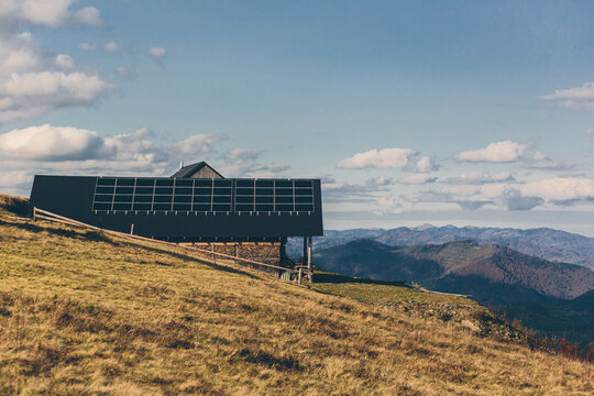 photo of a house in the mountains, on the roof of a solar panel, sunset