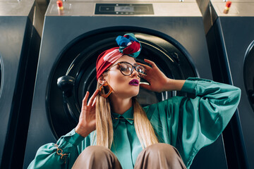 stylish young woman in glasses and turban looking away near washing machine