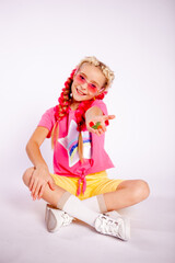 a cute girl in bright colorful clothes and with colored braids shows gelatinous gummies