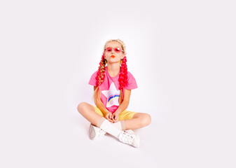 a cute girl in bright colorful clothes and with colored braids shows gelatinous gummies