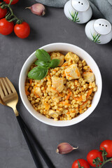 Homemade ptitim pasta with chicken and vegetables on dark gray table. Top view. Vertical format.