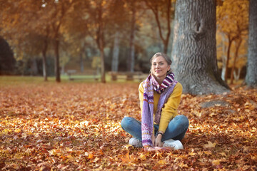 young woman sitting on the ground in an autumn park