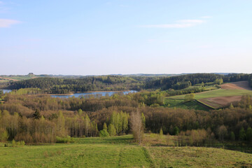 Fototapeta na wymiar The panorama of the Suwalki Region. Suwalki Region, Poland. View of green meadows, hills, trees and the lake