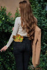 Girl in a brown raincoat with long black hair in the autumn park.