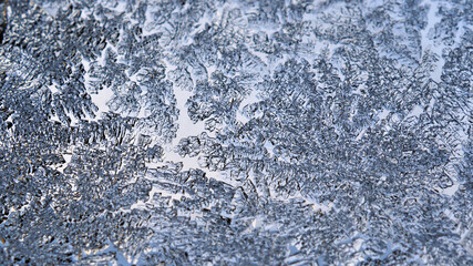 Ice crystals close up on a window glass in winter. Frozen water. Mystical fabulous abstract pattern. Weather forecast: frost, cooling. Blue background or wallpaper. Strong macro