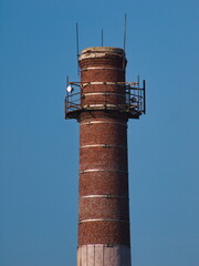 Old brick smokestack on sky blue background - 388615030