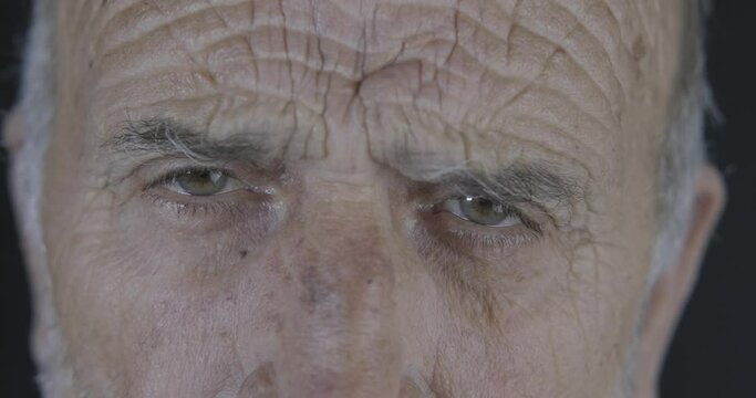Angry old man close up macro eyes. Face of elderly senior guy, serious face looking to camera, close up face portrait.