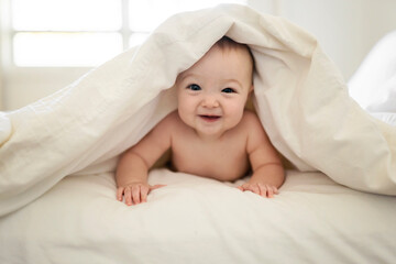 Fototapeta na wymiar Portrait of a baby under blanket on the bed in parent bedroom