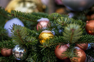 The Christmas tree is decorated with gold, silver and red balls. On the branches lies snow and drops of water. New year holiday photo.