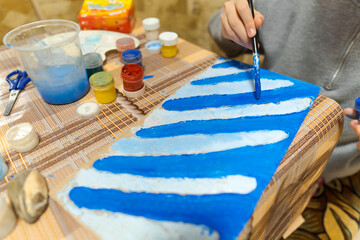 the girl draws blue gouache cardboard, makes a abstract background, sits in the home kitchen