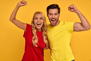Joyful young couple two friends guy and girl in red and yellow casual clothes posing isolated on...