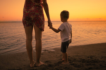 Mother and child watching the sunset on the beach 