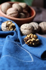 walnuts scattered from the bowl on a blue and brown cotton kitchen cloth are photographed in dark mode.