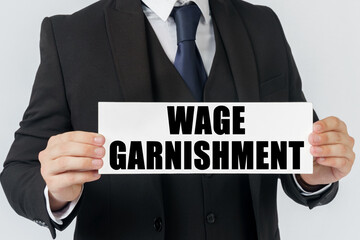 A businessman holds a sign in his hands which says WAGE GARNISHMENT