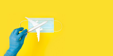 Hand in glove holding model airplane over face mask. Air travel resumes after travel. Open borders, quarantine end.