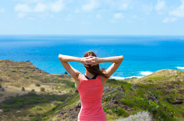 Happy woman with arms over head looking out to a beautiful ocean view