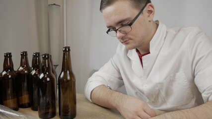 young master technologist brews beer at home, pours beer into bottles, checks the sugar level in beer, checks the percentage of alcohol in beer, checks the quality of the brewed