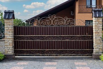 Modern strong decorative gates with wrought iron elements near a residential building.